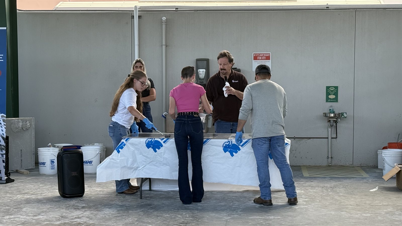 Students using trowels at a training table while a construction professional explains the technique