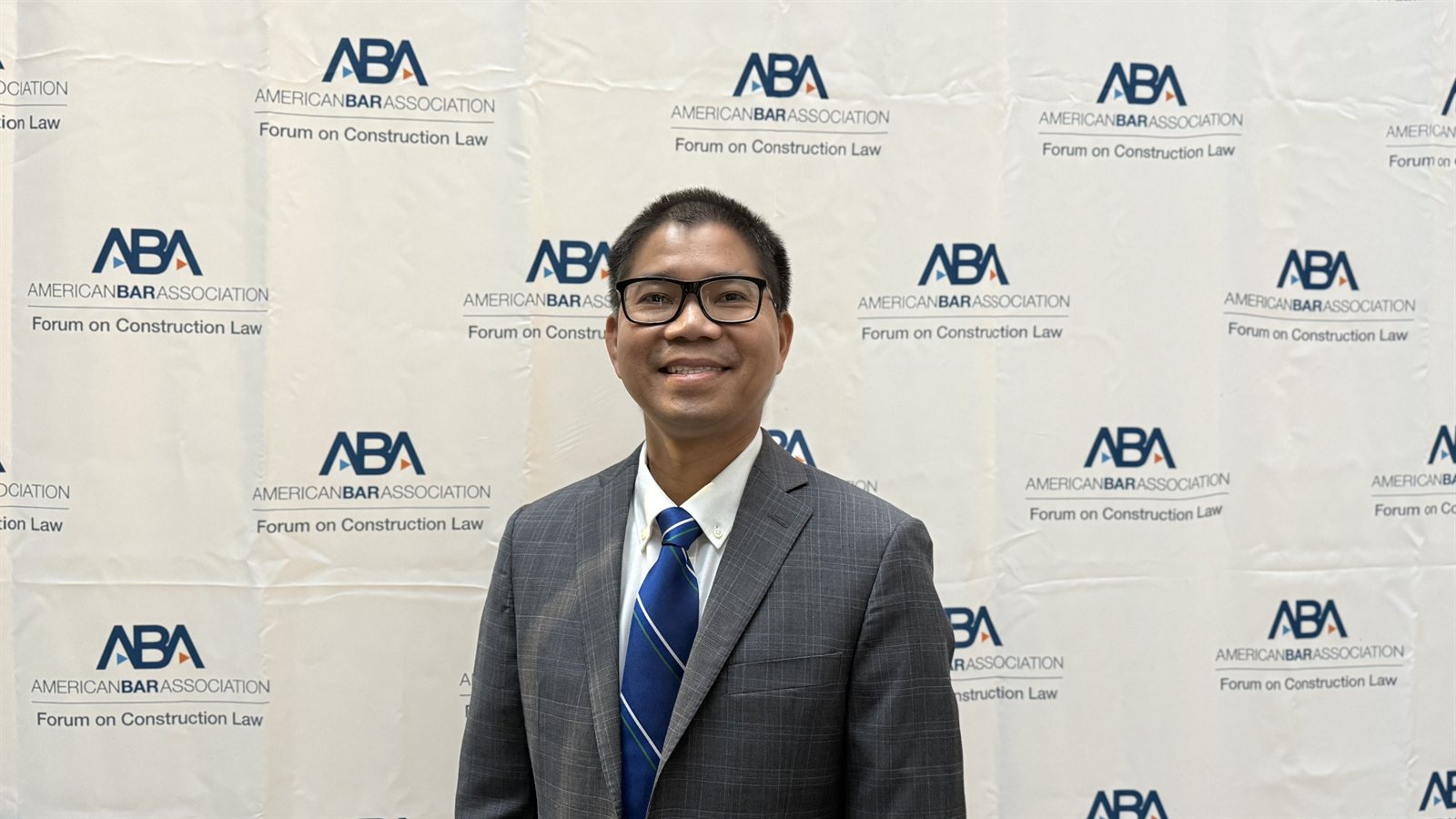 Dr. Nguyen in front of the ABA Forum on Construction Law backdrop in Tampa