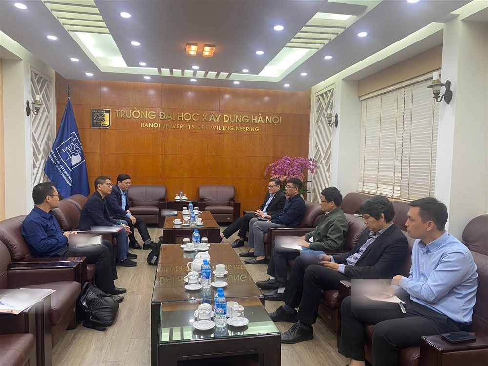 Academic colleagues meeting at Hanoi University of Civil Engineering; papers obscured