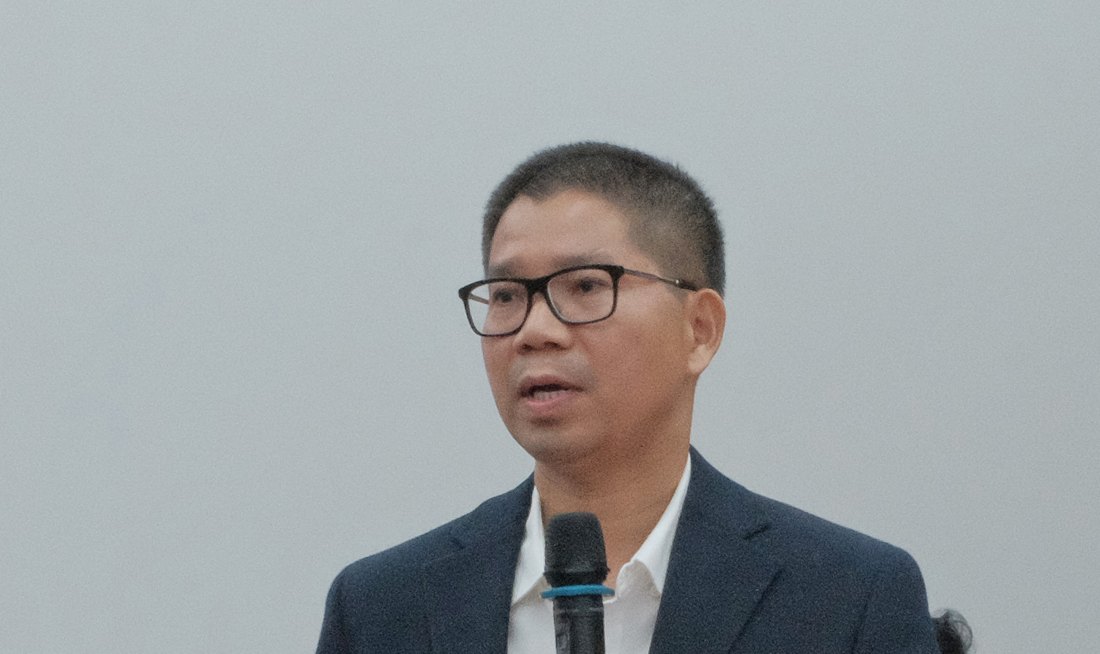 Dr. Nguyen speaking with a microphone during a construction seminar